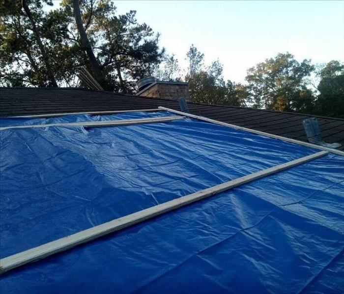 the blue tarp is secured to the damaged roof