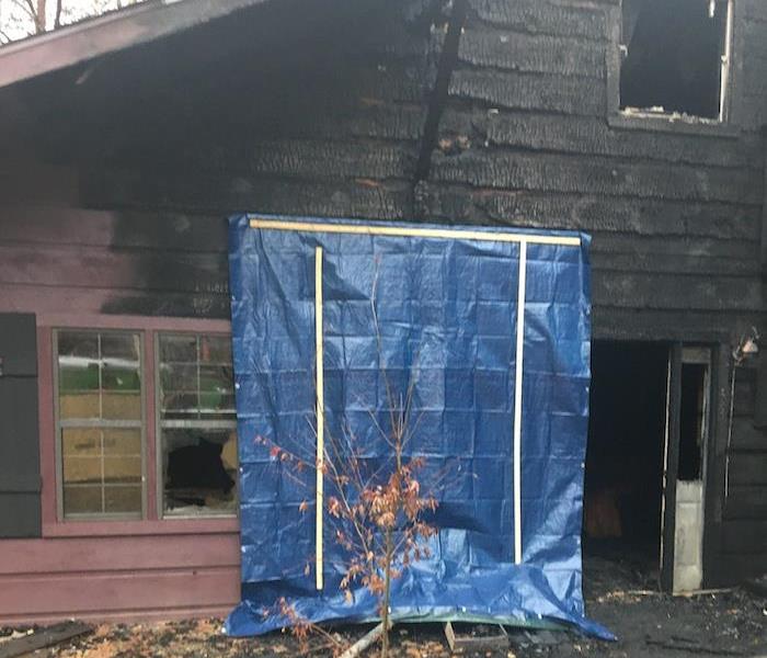 Residence with fire damage and a tarp over a window
