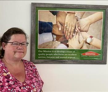 SERVPRO employee in front of photo frame and beige background. 