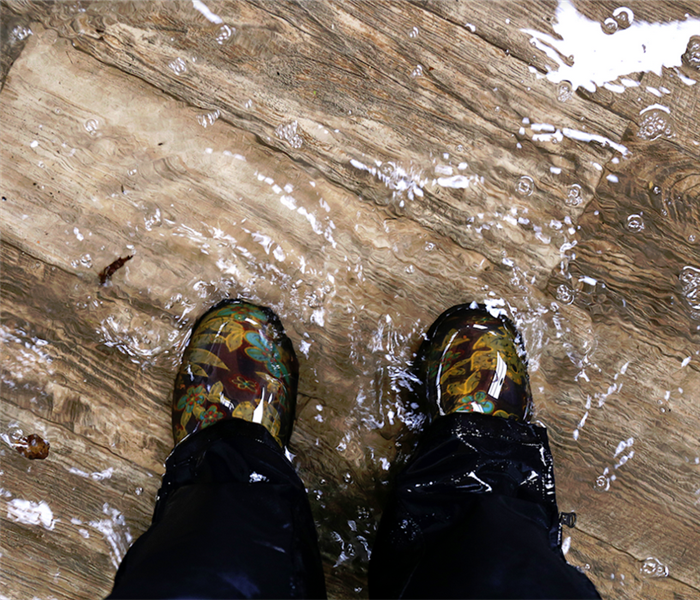 a flooded floor with someone standing in it with rain boots on
