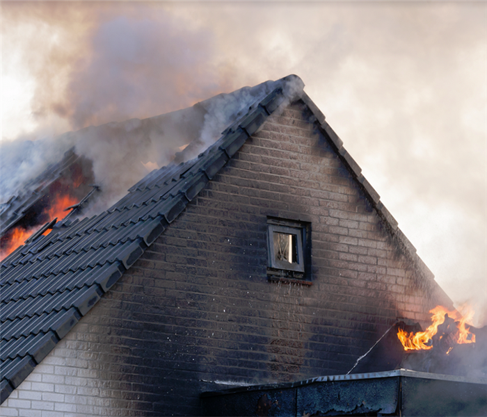 a house on fire with smoke and flames coming out of the windows and skylights